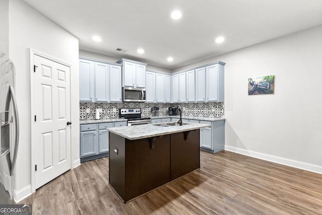 kitchen featuring sink, a breakfast bar, appliances with stainless steel finishes, an island with sink, and dark hardwood / wood-style flooring