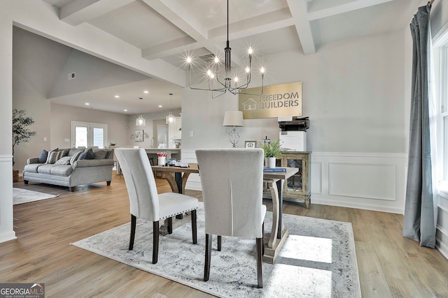 dining room with light wood-type flooring, a chandelier, and beam ceiling