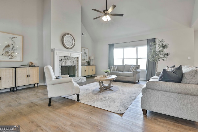 living room with high vaulted ceiling, a fireplace, hardwood / wood-style flooring, and ceiling fan