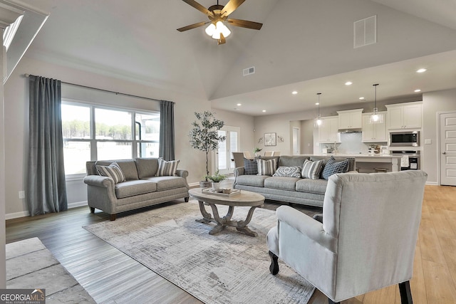 living room featuring light hardwood / wood-style floors, ceiling fan, and high vaulted ceiling