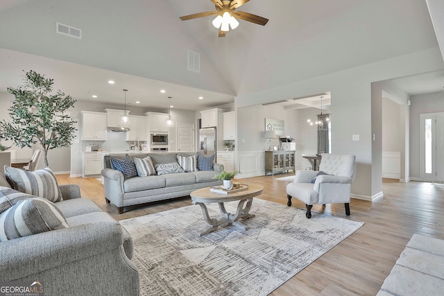 living room featuring high vaulted ceiling, light wood-type flooring, and ceiling fan with notable chandelier