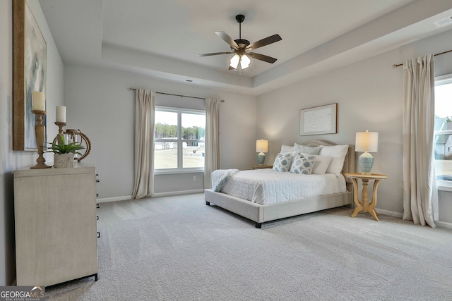 carpeted bedroom featuring ceiling fan and a raised ceiling