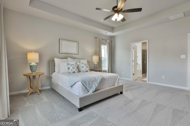 carpeted bedroom featuring ceiling fan, connected bathroom, and a raised ceiling