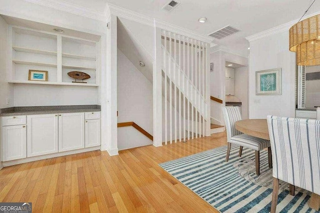 dining space featuring built in shelves, light hardwood / wood-style flooring, and ornamental molding