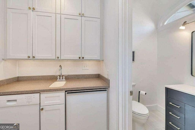 kitchen featuring white dishwasher, white cabinetry, sink, and tile patterned floors