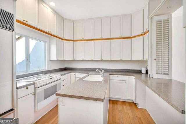 kitchen featuring built in fridge, white cabinets, white electric stove, sink, and light hardwood / wood-style floors