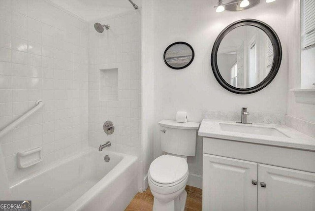 full bathroom with tiled shower / bath combo, toilet, wood-type flooring, and vanity