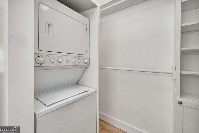 laundry room featuring stacked washer and dryer and light wood-type flooring