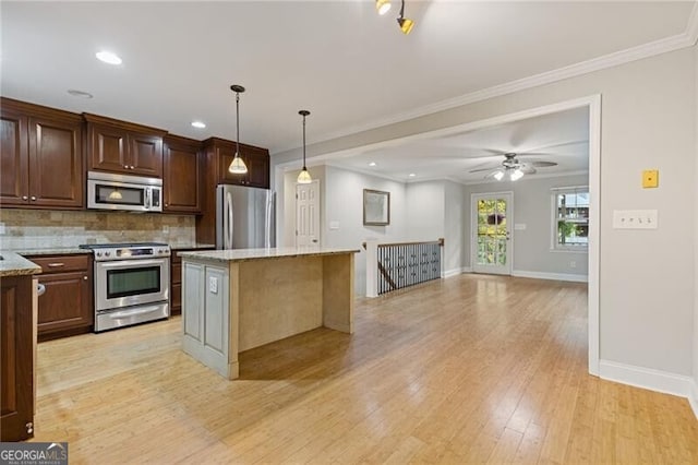 kitchen with light stone counters, stainless steel appliances, decorative light fixtures, a center island, and light hardwood / wood-style floors