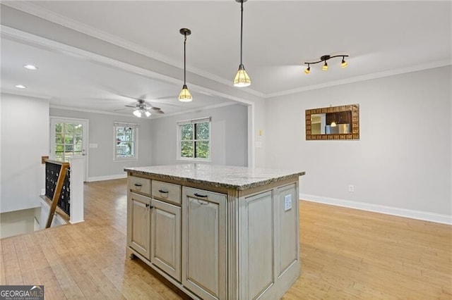 kitchen featuring light stone counters, a kitchen island, ornamental molding, and light wood-type flooring