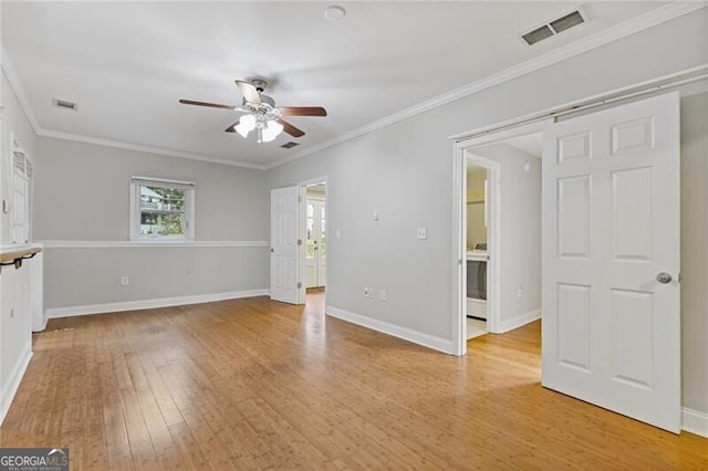 unfurnished room with ceiling fan, light hardwood / wood-style floors, a barn door, and ornamental molding