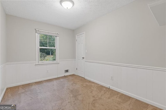 carpeted spare room featuring a textured ceiling