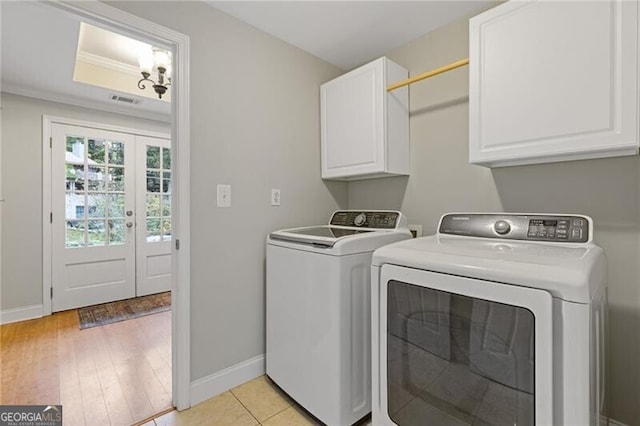 clothes washing area with cabinets, washing machine and clothes dryer, crown molding, and light hardwood / wood-style flooring