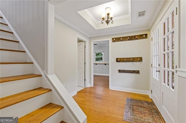 interior space with a chandelier, hardwood / wood-style flooring, crown molding, and a tray ceiling