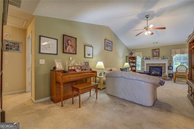 carpeted living room with ceiling fan, lofted ceiling, and a stone fireplace