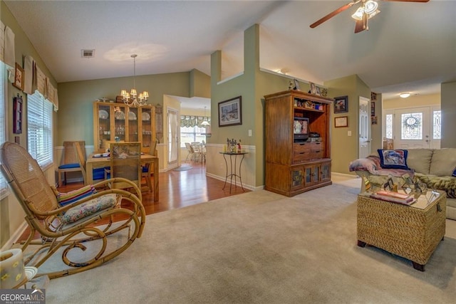 living room featuring vaulted ceiling, ceiling fan with notable chandelier, and light carpet