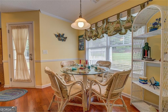 dining space with wood-type flooring, crown molding, and a textured ceiling