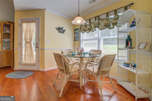 dining space featuring crown molding, wood-type flooring, and a textured ceiling