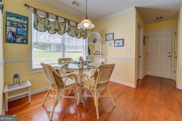 dining space featuring crown molding and wood-type flooring