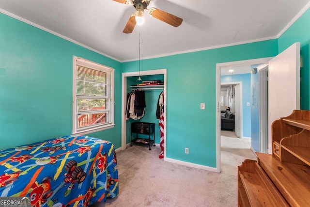 carpeted bedroom with a closet, ceiling fan, and crown molding