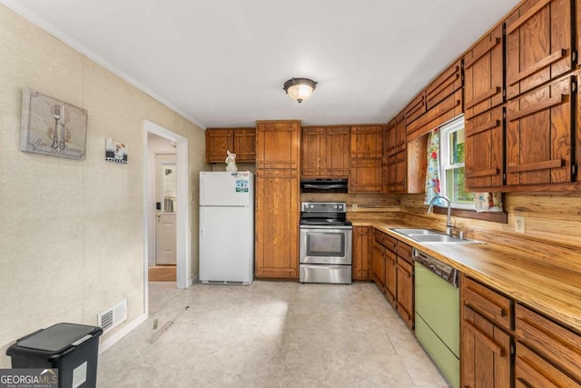 kitchen with sink, ornamental molding, range hood, and appliances with stainless steel finishes