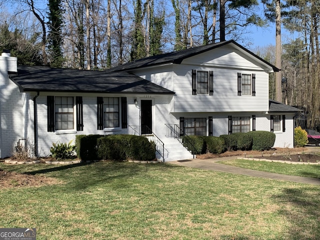 split level home with brick siding and a front yard