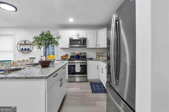 kitchen featuring stainless steel appliances, light hardwood / wood-style floors, white cabinets, and light stone counters