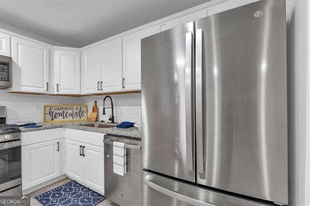 kitchen featuring white cabinets, appliances with stainless steel finishes, sink, and backsplash