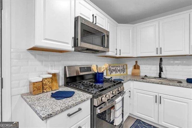 kitchen featuring white cabinetry, stainless steel appliances, sink, and tasteful backsplash