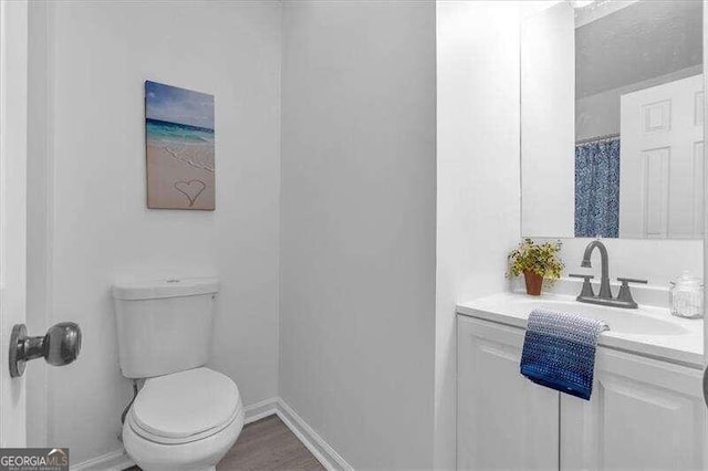 bathroom with hardwood / wood-style flooring, vanity, and toilet