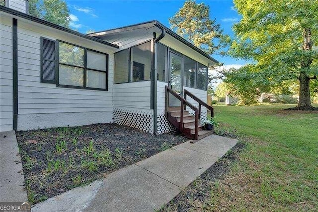 view of side of home with a sunroom and a yard