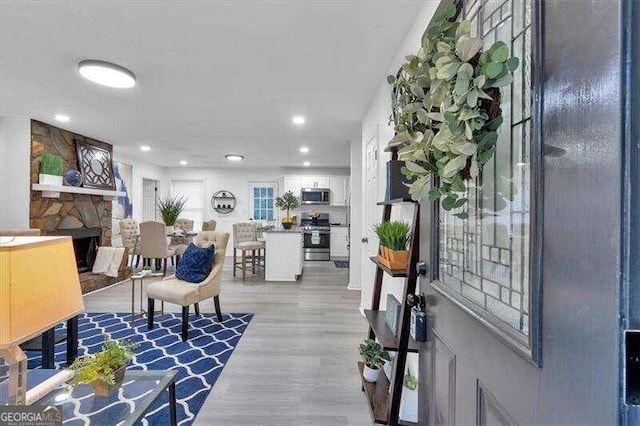 living room featuring a stone fireplace and light hardwood / wood-style flooring