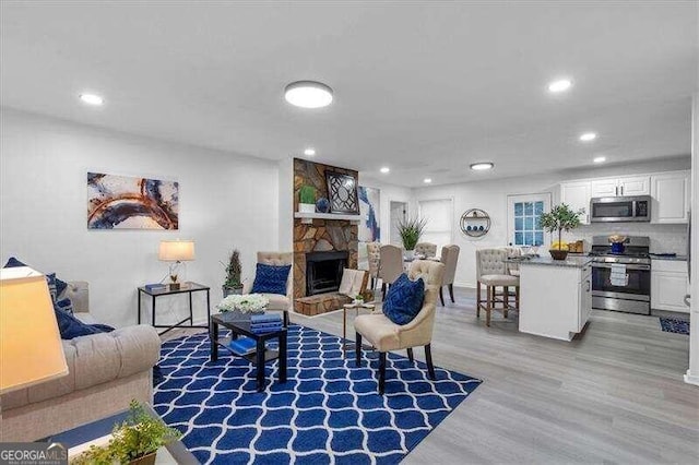 living room with a stone fireplace and light hardwood / wood-style flooring