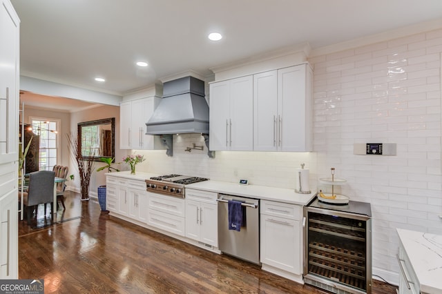 kitchen featuring appliances with stainless steel finishes, dark hardwood / wood-style floors, custom exhaust hood, beverage cooler, and white cabinets