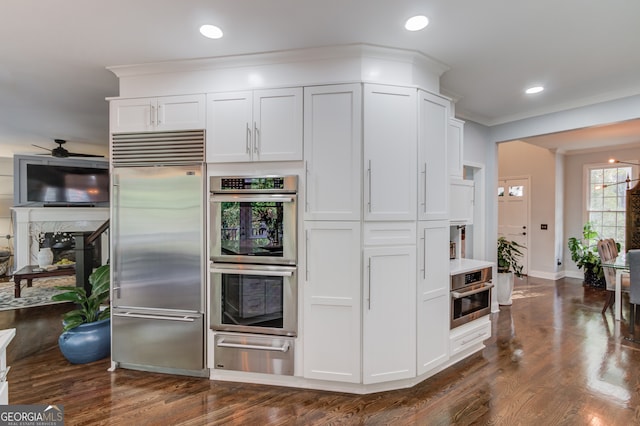 kitchen with white cabinets, dark hardwood / wood-style flooring, ceiling fan, and appliances with stainless steel finishes