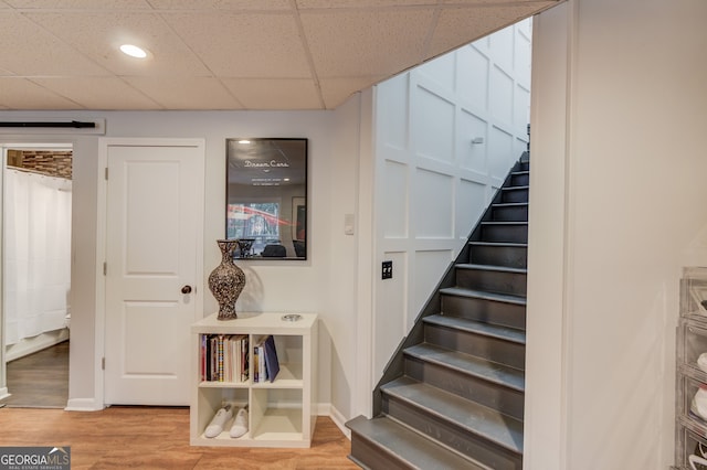 stairway with a paneled ceiling and hardwood / wood-style flooring