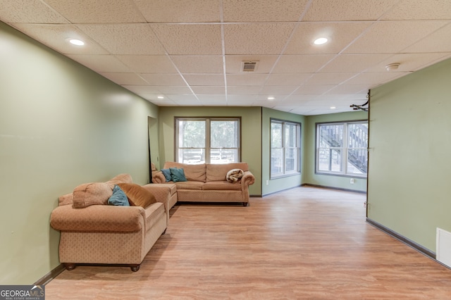 living room featuring light wood-type flooring and a paneled ceiling