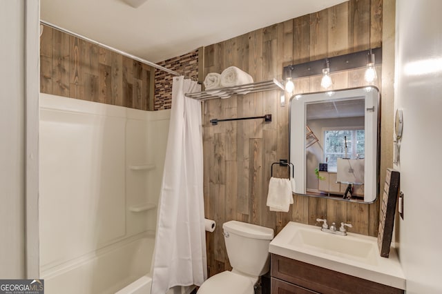 full bathroom with wood walls, shower / bath combo with shower curtain, toilet, and vanity