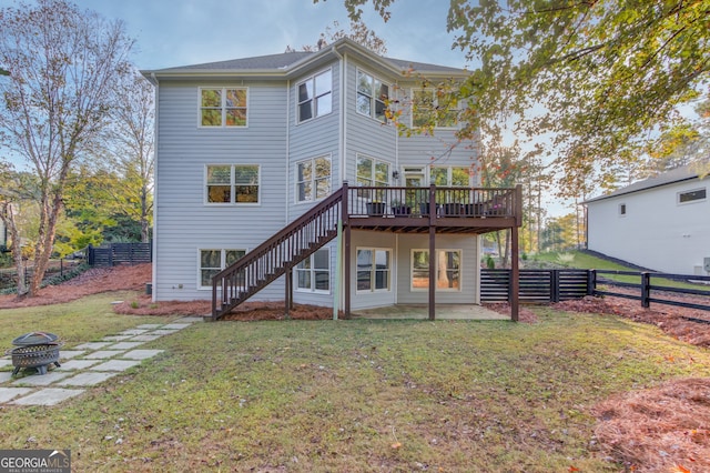 back of property with a fire pit, a lawn, a patio area, and a deck