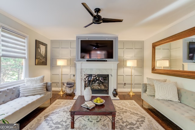 living room with dark wood-type flooring, a high end fireplace, ceiling fan, and ornamental molding