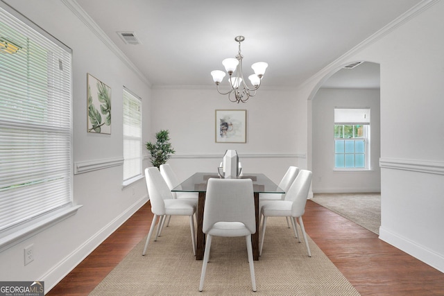 dining area featuring hardwood / wood-style flooring, a notable chandelier, and ornamental molding