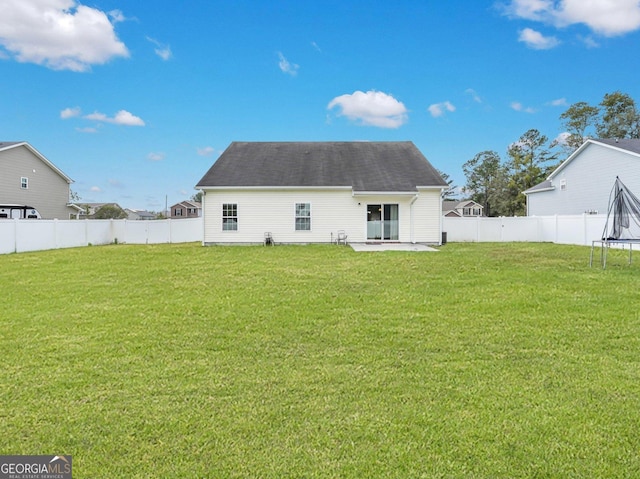 back of property with a trampoline, a lawn, and a patio