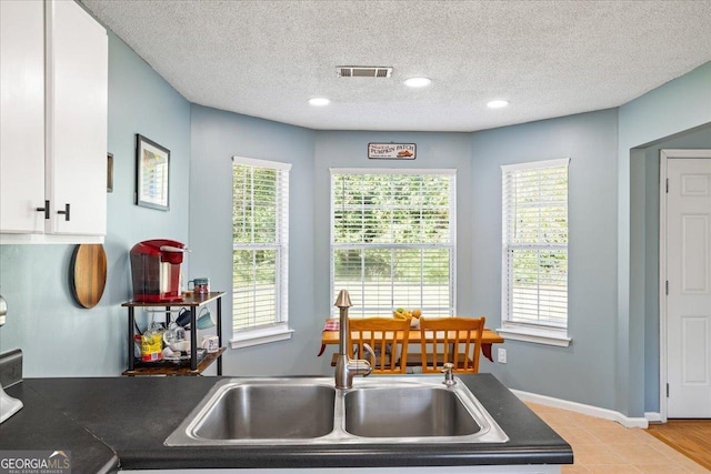 kitchen featuring a textured ceiling, light wood-type flooring, white cabinetry, and sink