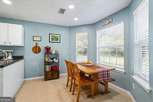 dining area with light tile patterned floors, a textured ceiling, and a healthy amount of sunlight