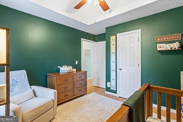 bedroom featuring ceiling fan, a nursery area, and light hardwood / wood-style flooring