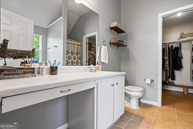 bathroom with tile patterned floors, vanity, vaulted ceiling, toilet, and curtained shower