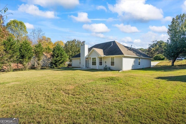 rear view of property featuring a yard, a garage, and cooling unit