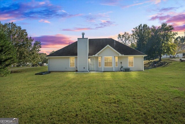 back house at dusk with a lawn