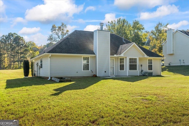 back of property with central AC unit and a yard