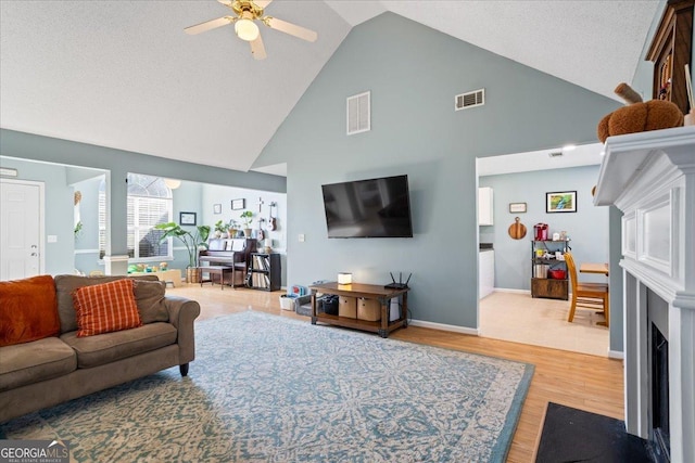 living room with ceiling fan, light wood-type flooring, and high vaulted ceiling